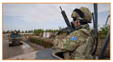 Photo of an armed soldier in combat gear patrolling in a tank.