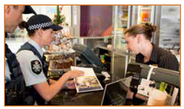 Photo of police personnel speaking to a shop-keeper.